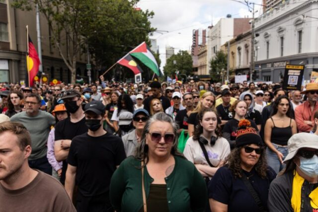 Uma multidão de manifestantes em Melbourne em um comício do Dia da Invasão.  Eles estão carregando bandeiras aborígines