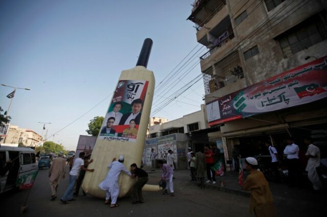 Apoiadores de Imran Khan, jogador de críquete paquistanês que virou político e presidente do partido político Paquistão Tehreek-e-Insaf (PTI), instalam um símbolo de morcego gigante ao longo de uma estrada em Karachi.