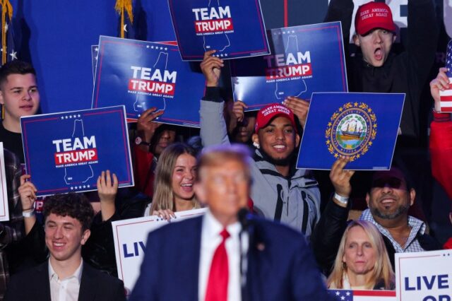 Apoiadores de Donald Trump comemoram enquanto ele fala em um pódio durante um comício em New Hampshire
