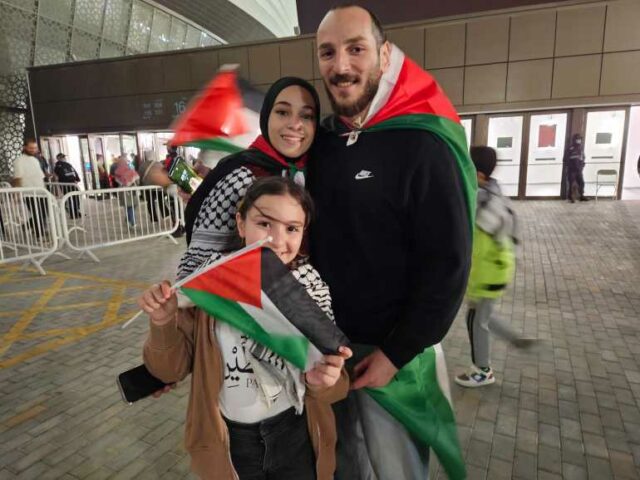 Abdullah Al Hind e sua esposa Mariana fora do estádio com uma bandeira da Palestina