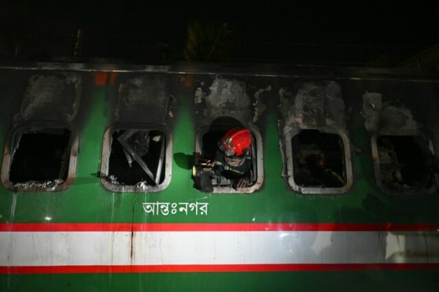 Um socorrista de Bangladesh aponta sua tocha para fora de uma janela enquanto revista um vagão queimado do Benapole Express em Dhaka, em 5 de janeiro de 2024