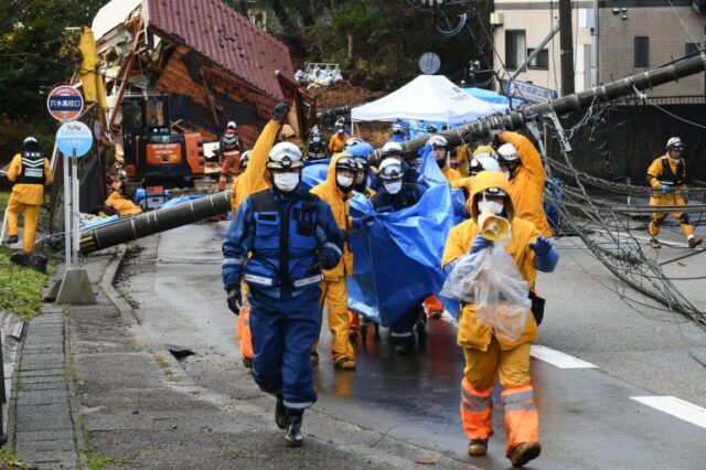 Equipes de resgate carregam o corpo da vítima que foi resgatada de um deslizamento de terra no distrito de Kawashima, na cidade de Anamizu, província de Ishikawa, em 6 de janeiro de 2024, após um grande terremoto de magnitude 7,5 atingir a região de Noto no dia de Ano Novo.
