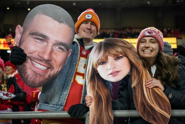 Os fãs do Chiefs acenam para Taylor Swift e Travis Kelce no Arrowhead Stadium.