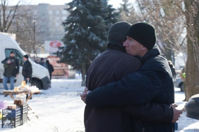 Dois homens se abraçam no local de um ataque com mísseis em Donetsk, em 21 de janeiro