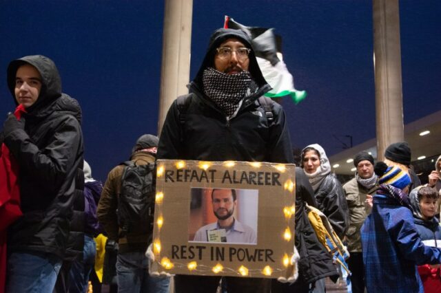 Homem protestando com cartaz que tem a foto de Alareer