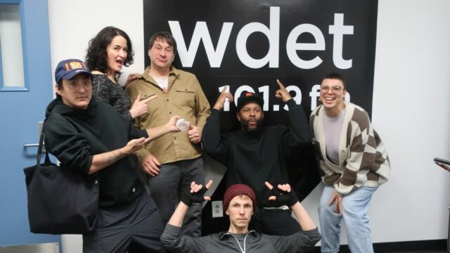 Novos apresentadores musicais do WDET posam em frente ao logotipo do WDET.