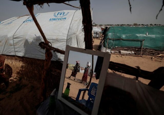 Mulheres sudanesas que fugiram do conflito na região sudanesa de Darfur transportam os seus alimentos enquanto caminham em direção aos seus abrigos improvisados ​​em Adre, no Chade