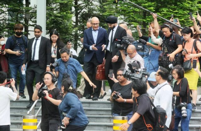 O ex-ministro dos Transportes de Cingapura, S Iswaran, deixando o tribunal.  Ele está cercado por jornalistas. 