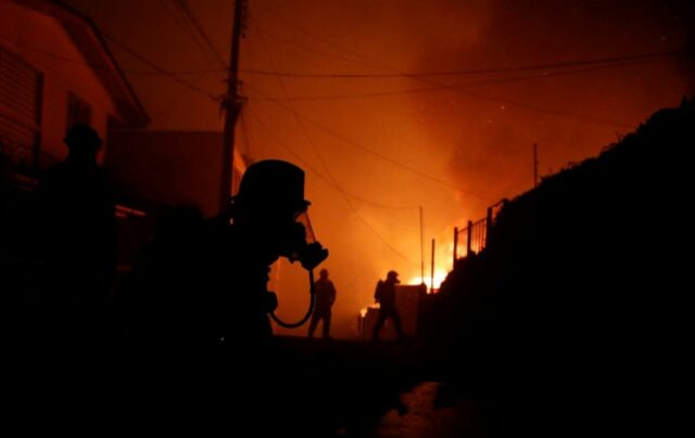 Bombeiros tentam apagar um incêndio em Viña del Mar, Chile, em 2 de fevereiro de 2024. Uma enorme nuvem de fumaça em forma de cogumelo paira sobre áreas turísticas no centro do Chile, incluindo Viña del Mar e Valparaíso, onde eclodiu um incêndio florestal na sexta-feira, ameaçando centenas de casas e forçando a evacuação dos residentes.  (Foto de Javier TORRES/AFP)