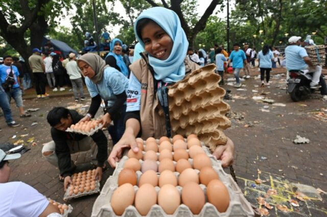 Uma mulher mostrando uma bandeja de ovos que ganhou após um comício de campanha na Indonésia.