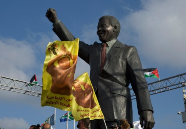 Manifestantes agitam faixas com uma foto do líder do levante palestino preso, Marwan Barghouti, sob uma estátua de Nelson Mandela, durante uma manifestação de apoio à fome em greve de prisioneiros palestinos nas prisões israelenses, que estão em greve de fome por tempo indeterminado nos últimos 17 dias, no Cidade de Ramallah, na Cisjordânia, quarta-feira, 3 de maio de 2017. Os prisioneiros lançaram o protesto para pressionar por melhores condições, incluindo visitas familiares.  Leituras árabes 