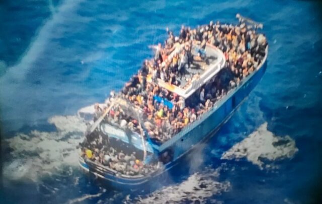 dezenas de pessoas cobrindo praticamente todos os trechos livres do convés de um barco de pesca danificado que mais tarde virou e afundou no sul da Grécia