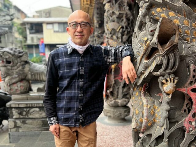 IHua Wu ao lado de uma estátua de dragão em um templo em Taipei, Taiwan. 