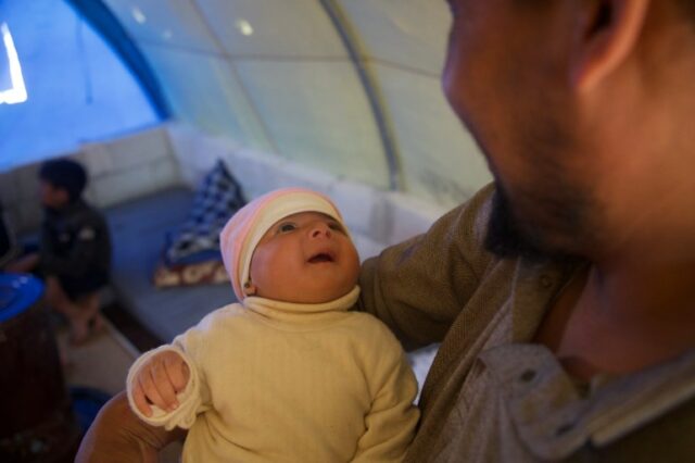Afraa olha para seu tio arrulhando na tenda da família (Ali Haj Suleiman/Al Jazeera)