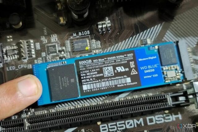 Uma imagem que mostra uma pessoa segurando um módulo SSD M.2 no lugar com o dedo.