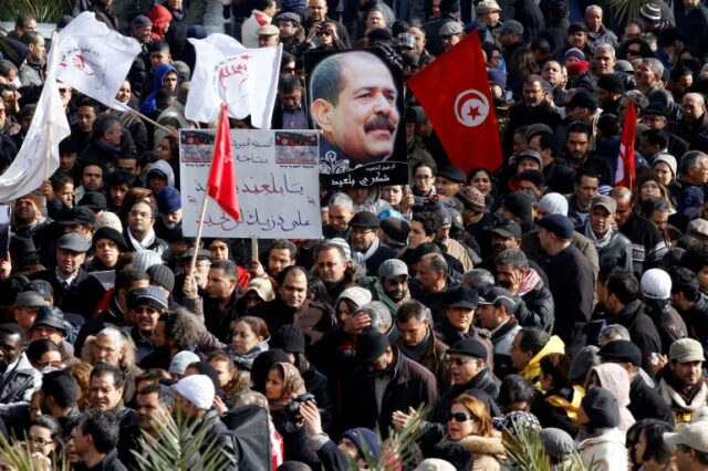 Unisianos seguram um cartaz com a imagem do falecido líder da oposição secular Chokri Belaid durante seu cortejo fúnebre no distrito de Jebel Jelloud, em Túnis