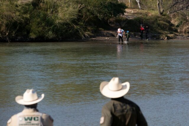 Uma família de migrantes cruza o rio Rio Grande logo atrás da entrevista coletiva de um legislador republicano criticando as políticas de imigração do governo Biden durante uma visita a Eagle Pas