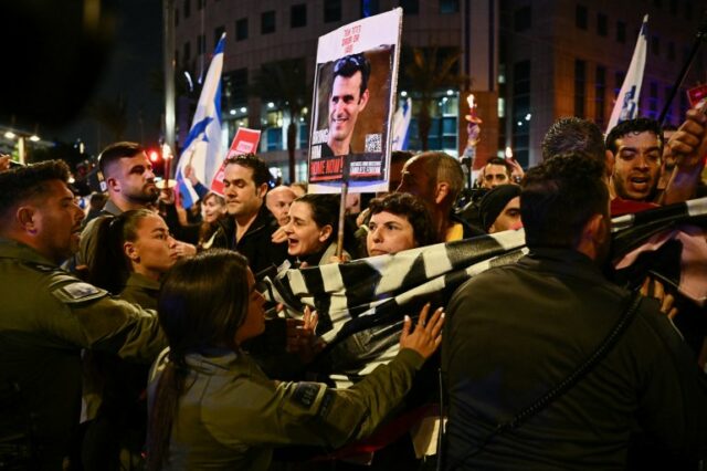 Pessoas ficam na frente de um policial durante um protesto contra o governo do primeiro-ministro israelense, Benjamin Netanyahu