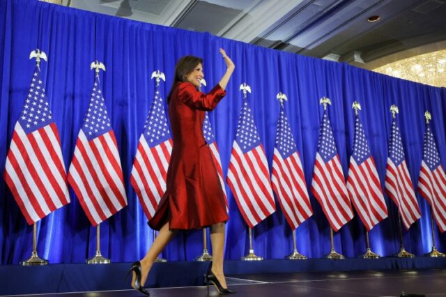 Nikki Haley sobe ao palco em frente a uma fileira de bandeiras dos EUA.