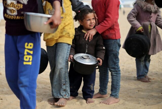 Crianças palestinas deslocadas esperam para receber comida em um acampamento em Rafah, no sul da Faixa de Gaza, em 27 de fevereiro de 2024.