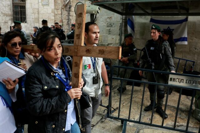 Fiéis carregam uma cruz enquanto participam da procissão da Sexta-Feira Santa na Via Dolorosa, na Cidade Velha de Jerusalém