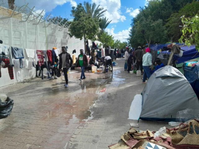 A passagem onde os refugiados estão acampados.  Está lotado e um vazamento deixa o chão molhado