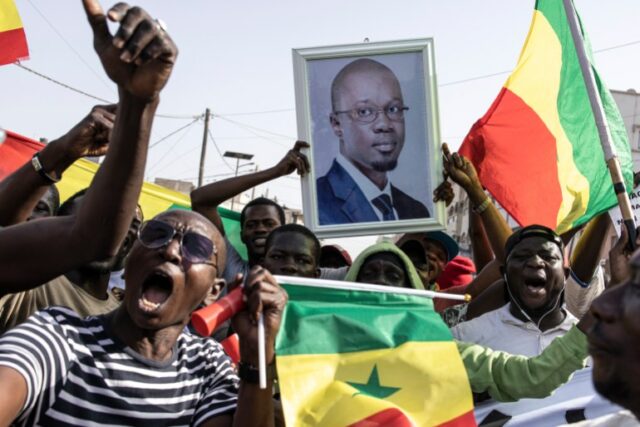 Apoiadores da oposição cantam e dançam durante uma reunião dois dias antes do julgamento de um dos líderes, Ousmane Sonko, em Dakar, em 14 de março de 2023. (Foto de JOHN WESSELS / AFP)