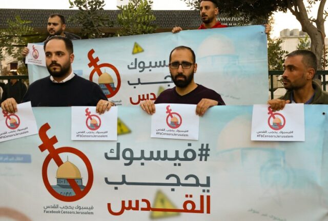 Ativistas e jornalistas palestinos seguram cartazes com a hashtag de sua campanha '#FBCensorsJerusalem' enquanto protestam contra o que consideram censura por parte do meio de comunicação social Facebook de conteúdo palestino, na cidade ocupada de Hebron, na Cisjordânia, em 24 de novembro de 2021