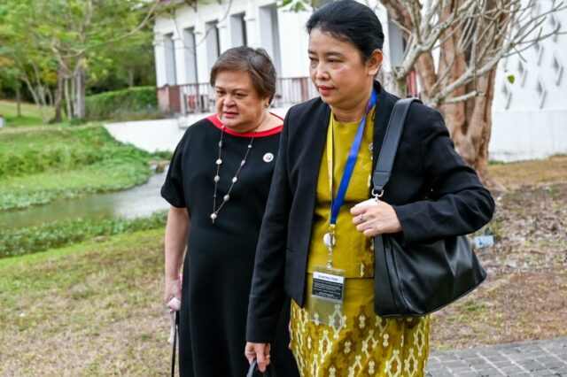 Oficial do Ministério das Relações Exteriores de Mianmar, Marlar Than Htike, em Luang Prabang.  Ela está caminhando com um oficial das Filipinas. Ela está vestindo uma roupa tradicional com uma jaqueta e com a bolsa pendurada no ombro.