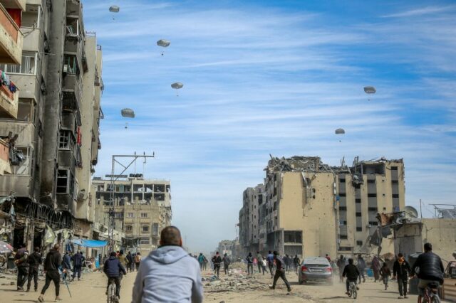 Palestinos correm ao longo de uma rua enquanto ajuda humanitária é lançada por via aérea na Cidade de Gaza em 1º de março