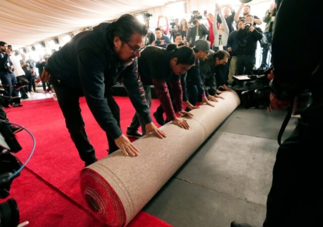Membros da equipe desenrolam um rolo de tapete vermelho no local da 96ª edição anual do Oscar.