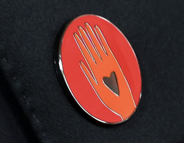 Um distintivo vermelho usado para pedir um cessar-fogo em Gaza chegando no tapete vermelho da 96ª edição do Oscar no Dolby Theatre em Hollywood 
