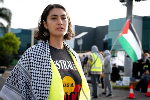 Organizadora comunitária Nathalie Farah.  Ela está usando um lenço palestino e uma camiseta preta que diz Austrália. 