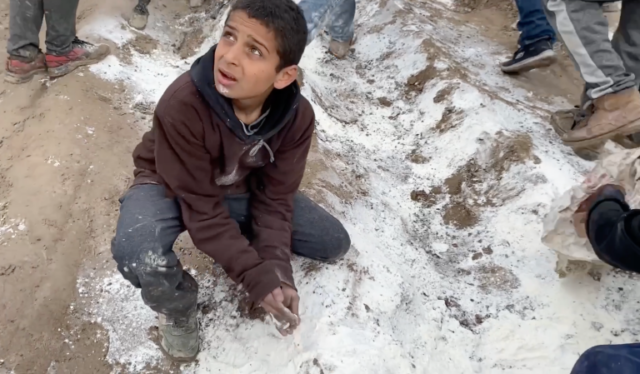 Uma criança palestiniana tenta recolher farinha derramada durante a distribuição de ajuda no norte de Gaza.  (Captura de tela/Al Jazeera)