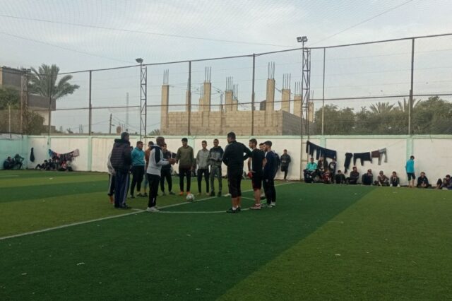Duas equipes se reúnem no meio do campo antes do início de uma partida durante um torneio de futebol do Ramadã no Al-Salah Football Club, em Gaza (Abubaker Abed/Al Jazeera)