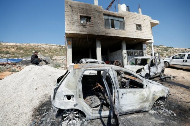 Um homem palestino sentado perto de uma casa e carros danificados depois que colonos israelenses atacaram a vila de al-Mughayyer, na Cisjordânia ocupada por Israel, 13 de abril de 2024