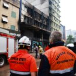 Membros da defesa civil no local de um incêndio mortal em uma pousada em Porto Alegre