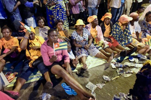 Apoiantes da oposição togolesa sentam-se numa rua enquanto fazem vigília durante toda a noite para pressionar pela reforma constitucional em 2017