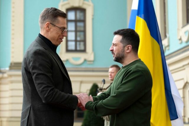 O presidente da Finlândia, Alexander Stubb, encontra-se com o presidente ucraniano Volodymyr Zelenskyy em Kiev.  Zelenskyy o dá as boas-vindas e eles apertam as mãos.  Uma bandeira ucraniana está atrás deles.