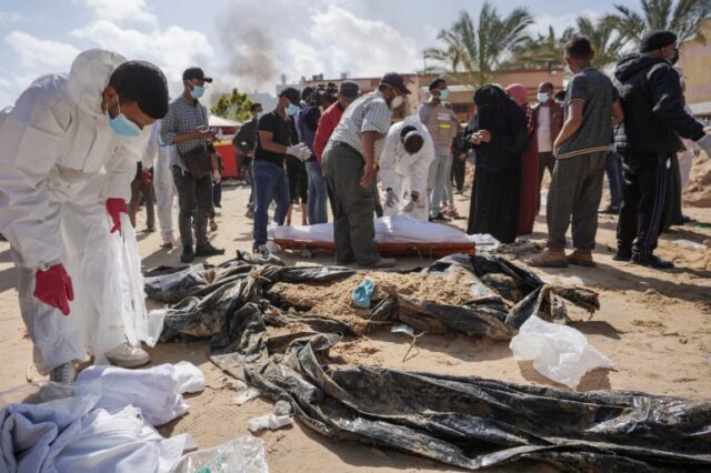 Profissionais de saúde palestinos ficam ao lado de corpos desenterrados enterrados pelas forças israelenses no hospital Nasser