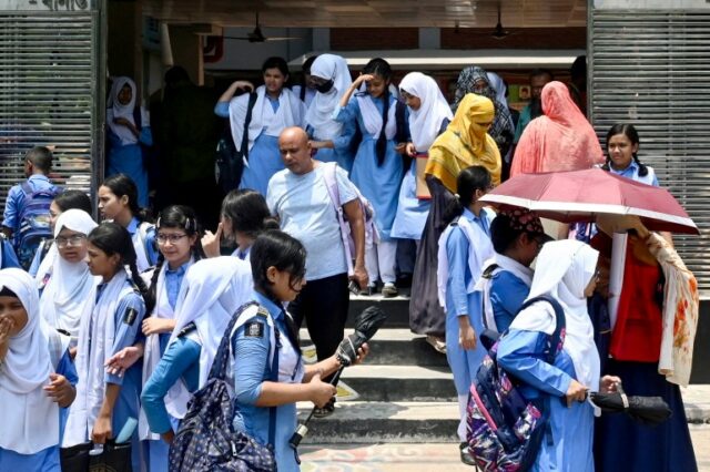 Os alunos que saem do complexo escolar carregam guarda-chuvas em um dia quente de verão em Dhaka, em 28 de abril de 2024, em meio à onda de calor contínua.  - Milhões de estudantes regressaram às suas escolas reabertas em Bangladesh em 28 de abril