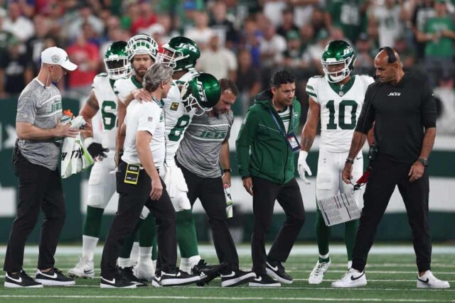 O quarterback Aaron Rodgers nº 8 do New York Jets é ajudado fora de campo pelos treinadores do time após uma lesão durante o primeiro quarto do jogo da NFL contra o Buffalo Bills no MetLife Stadium em 11 de setembro de 2023 em East Rutherford, Nova Jersey.
