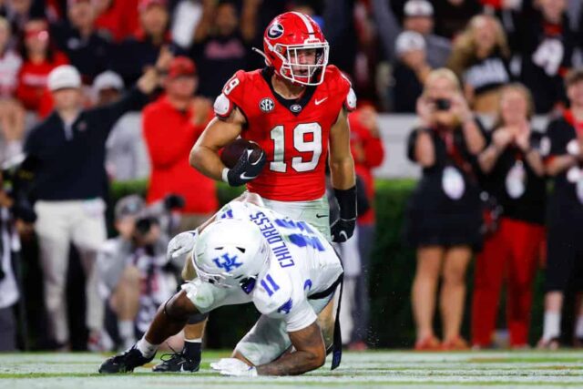 Brock Bowers #19 do Georgia Bulldogs marca um touchdown contra Zion Childress #11 do Kentucky Wildcats durante o terceiro quarto no Sanford Stadium em 7 de outubro de 2023 em Athens, Georgia.