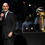 O comissário da NBA, Adam Silver, fala perto do Troféu Larry O'Brien enquanto o Denver Nuggets comemora seu campeonato com um levantamento de bandeira e uma cerimônia de toque antes do jogo contra o Los Angeles Lakers na Ball Arena em 24 de outubro de 2023 em Denver, Colorado.