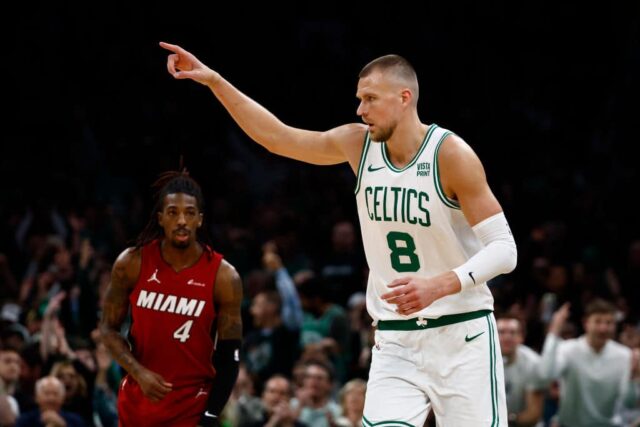 Kristaps Porzingis # 8 do Boston Celtics aponta para um companheiro de equipe depois de fazer uma cesta de três pontos enquanto Delon Wright # 4 do Miami Heat observa durante o primeiro quarto do jogo um dos Playoffs da Primeira Rodada da Conferência Leste no TD Garden em 21 de abril, 2024 em Boston, Massachusetts.