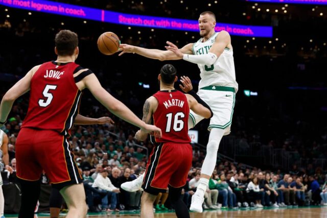 Kristaps Porzingis # 8 do Boston Celtics passa por Caleb Martin # 16 do Miami Heat durante a segunda metade do primeiro jogo dos Playoffs da Primeira Rodada da Conferência Leste no TD Garden em 21 de abril de 2024 em Boston, Massachusetts.