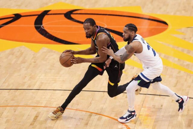 Kevin Durant #35 do Phoenix Suns passa a bola por Monte Morris #23 do Minnesota Timberwolves durante a segunda metade do terceiro jogo dos Playoffs da Primeira Rodada da Conferência Oeste no Footprint Center em 26 de abril de 2024 em Phoenix, Arizona.  Os Timberwolves derrotaram os Suns por 126-109.