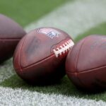 As bolas de futebol ficam na grama antes do início do jogo entre Baltimore Ravens e Houston Texans no M&T Bank Stadium em 10 de setembro de 2023 em Baltimore, Maryland.
