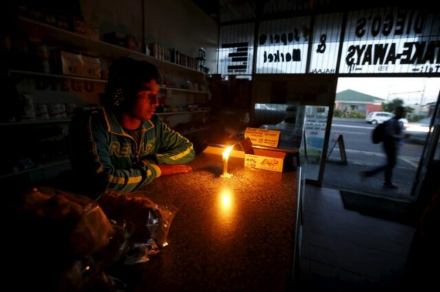 Um lojista na África do Sul trabalha à luz de velas durante um apagão