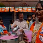 Apoiadores do Partido Bharatiya Janata (BJP), no poder, na Índia, distribuem bebidas doces fora de uma seção eleitoral durante as eleições em um dia quente de verão em Karnal, no estado de Haryana, no norte da Índia, em 25 de maio de 2024.